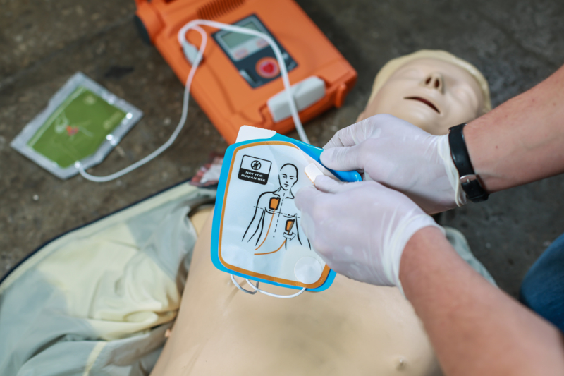 Person i gang med at påføre elektroder på en dukke på et kursus fra Securitas, der handler om at bruge en hjertestarter til erhverv